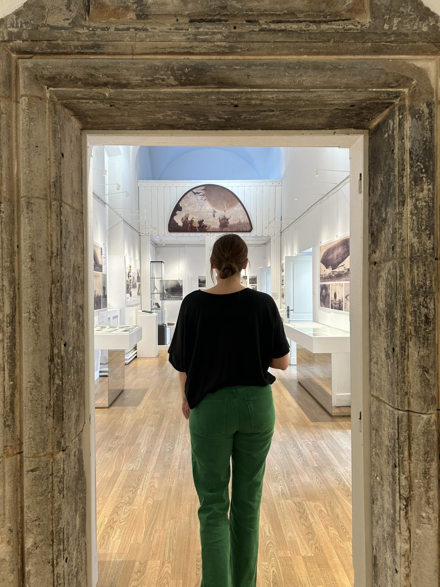 jeune femme dans l'embrasure d'une porte en pierre entrant dans une salle d'exposition de l'abbaye